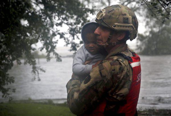 Rescue team member Sgt. Nick Muhar, from the North Carolina National Guard 1/120th battalion, evacuates a young child as the rising floodwaters from Hurricane Florence threatens his home in New Bern, N.C., on Sept. 14, 2018. (AP Photo/Chris Seward)