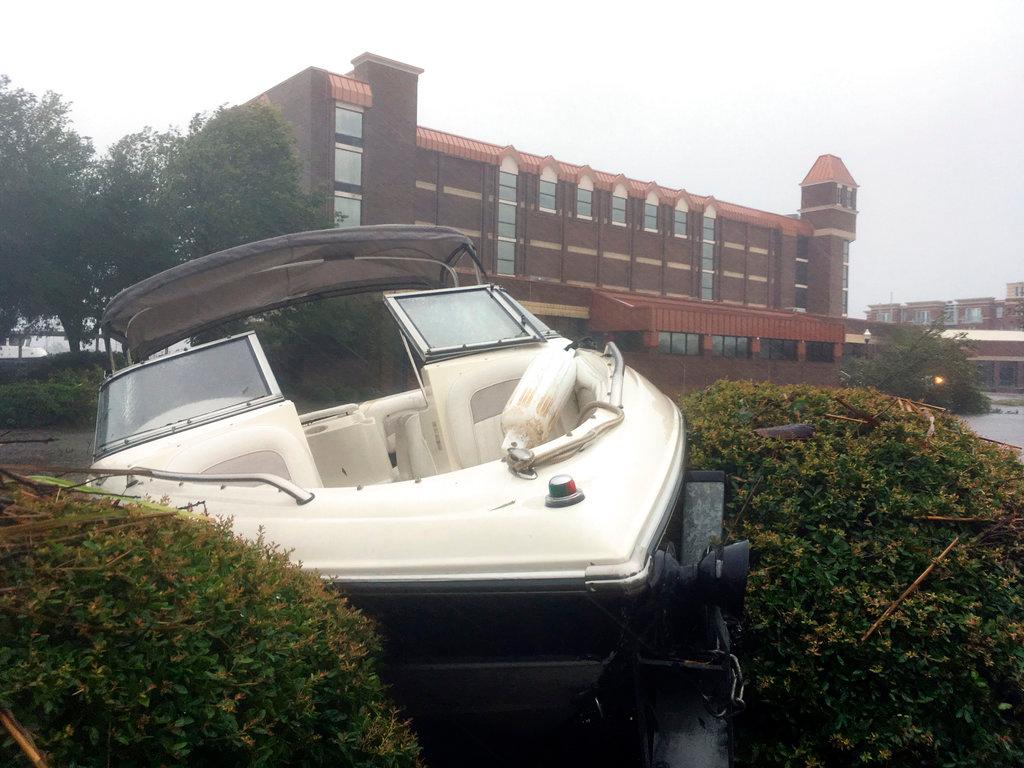 A speed boat sits wedged in bushes in the parking lot of a waterfront hotel in New Bern, N.C., on Sept. 14, 2018. (AP Photo/Allen G. Breed)