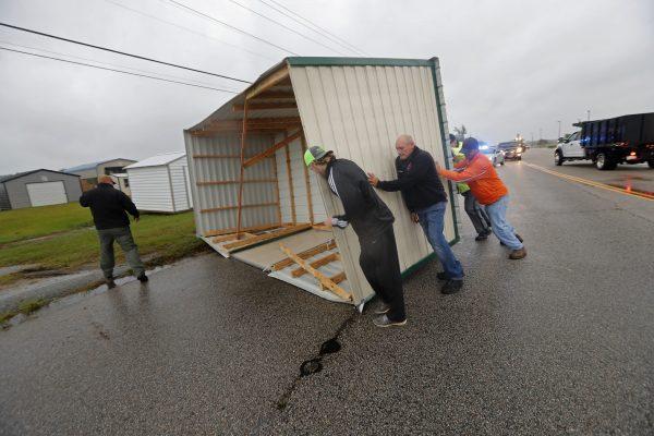 People move a wood and metal structure off a roadway after winds from Hurricane Florence blew it off a sales lot in Florence, S.C., on Sept. 14, 2018. (AP Photo/Gerald Herbert)