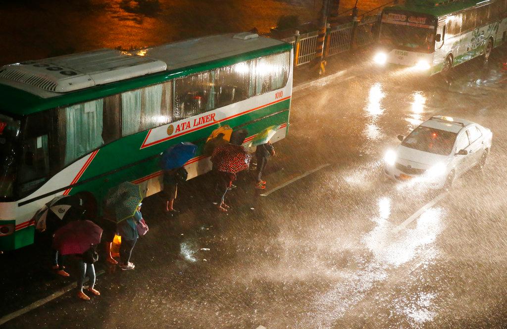 Commuters brave the rain and strong winds brought about by Typhoon Mangkhut which barrelled into northeastern Philippines before dawn on Sept. 15, 2018, in Manila, Philippines. (AP Photo/Bullit Marquez)