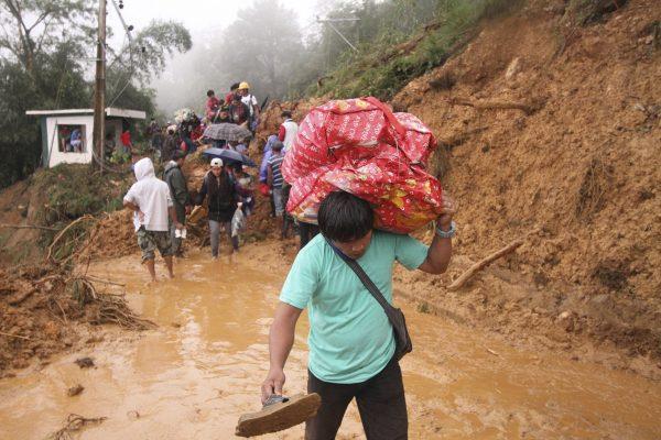 Families and relatives of miners carry their belongings as they evacuate following landslides which were triggered by Typhoon, burying an unknown number of miners and isolating the township in Itogon, Benguet province in the northern Philippines, on Sept. 16, 2018. (Photo by AP/Jayjay Landingin)