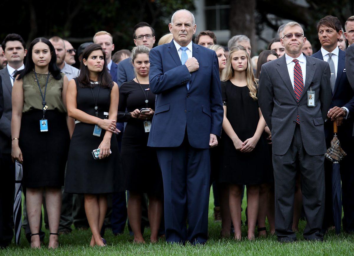 White House Chief of Staff John Kelly (C) places his hand over his heart during the playing of "Taps" as members of the White House observe a moment of silence on the south lawn of the White House at 8:37 a.m., the time the first tower was hit on 9/11, in Washington on Sept. 11, 2018. (Win McNamee/Getty Images)