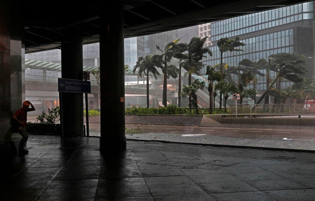 A worker, left, stands against strong wind caused by Typhoon Mangkhut in Hong Kong on Sept. 16, 2018. Hong Kong and southern China hunkered down as strong winds and heavy rain from Typhoon Mangkhut lash the densely populated coast. The biggest storm of the year left at least 28 dead from landslides and drownings as it sliced through the northern Philippines. (By Vincent Yu/AP Photo)