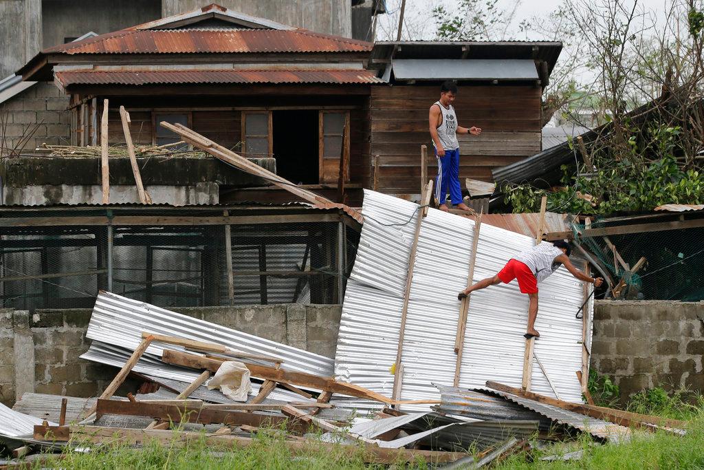 Residents work to repair a damaged roof due to strong winds from Typhoon Mangkhut after it barreled across Tuguegarao city in Cagayan province, northeastern Philippines on Sept. 16, 2018. Typhoon Mangkhut roared toward densely populated Hong Kong and southern China after ravaging across the northern Philippines with ferocious winds and heavy rain causing landslides and collapsed houses. (By Aaron Favila/AP Photo)