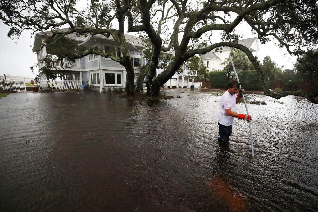 Mike Pollack searches for a drain in the yard of his flooded waterfront home a day after Hurricane Florence hit the area in Wilmington, North Carolina, on Sept. 15, 2018. (Photo by Mark Wilson/Getty Images)
