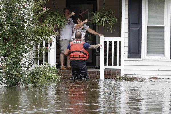 A member of the U.S. Coast Guard assists Roger and Susan Hedgepeth in Lumberton, N.C., Sunday, Sept. 16, 2018 following flooding from Hurricane Florence . (AP Photo/Gerry Broome)