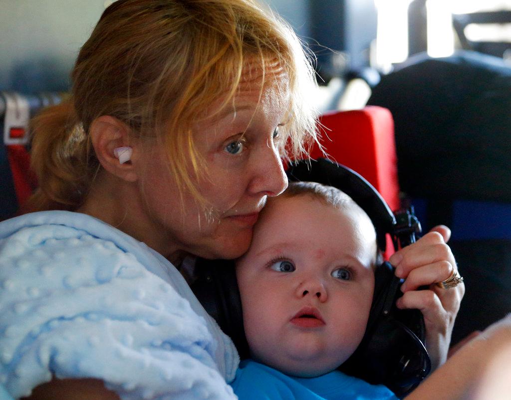 Catherine Riggs, holds her grandson Luke Humphrey as she listens to a briefing aboard a U.S. Coast Guard helicopter in Burgaw , N.C., on Sept. 18, 2018. (Steve Helber/AP Photo)