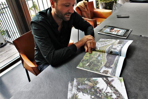 Frédéric Chartier, co-founder of Chartier Dalix Studio, in his Paris office. He is reading the booklet presenting one of his delivered projects incorporating urban farming, the Biodiversity School and Gymnasium at Boulogne Billancourt, near to Paris. (Alexia Luquet/Special to The Epoch Times)