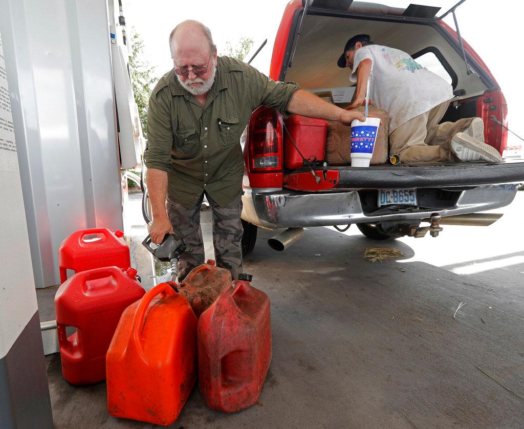 Willie Delong, of Holly Ridge, N.C., fills gas cans at a convenience store in Wilmington, N.C., on Sept. 17, 2018. (AP Photo/Chuck Burton)