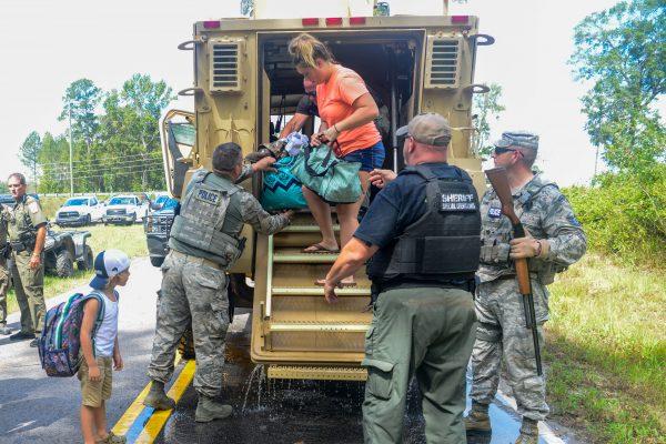 U.S. Air Force Security Forces airmen and Florence County Sheriff's Department assist local citizens off a tactical truck during evacuation efforts in Florence, South Carolina on Sept. 17, 2018. (U.S. Army National Guard/Staff Sgt. Jorge Intriago/Handout via Reuters)