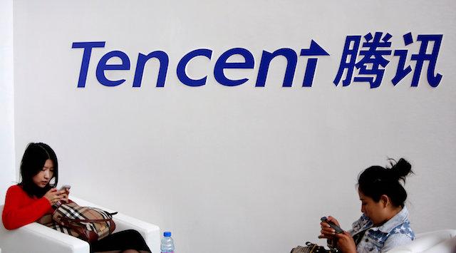 Visitors use their smartphones underneath the logo of Tencent at the Global Mobile Internet Conference in Beijing May 6, 2014. (Reuters/Kim Kyung-Hoon)