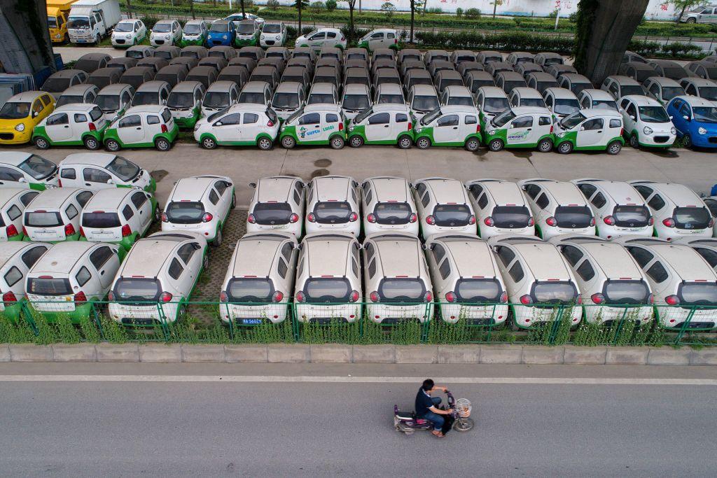 A motorist rides past new electric vehicles in Wuhan, Hubei Province, China, on May 22, 2017. (STR/AFP/Getty Images)