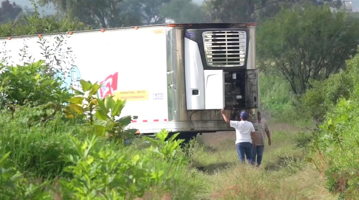 Men stand by an abandoned trailer full of bodies that has been parked in Tlajomulco de Zuniga, Jalisco, Mexico September 15, 2018 in this still image taken from a video obtained September 17, 2018. (By Reuters TV/Reuters)