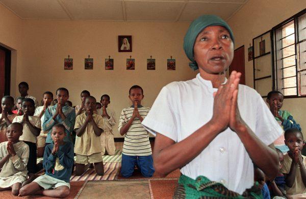 A nun of Mother Teresa's religious order, the Missionaries of Charity, prays on July 2, 1994, with orphans at the government-zone parish of French nun Sister Suzanne in Kigali, Rwanda. (Pierre Boussel/AFP/Getty Images)