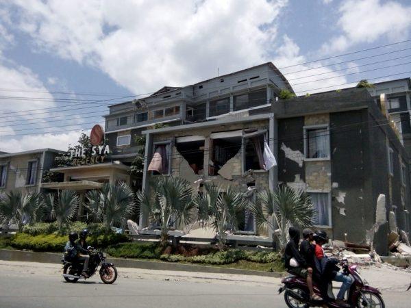 Young people drive a motorcycle near a damaged house after the earthquake hit in Palu, Indonesia, on Sept. 29, 2018. (Stringer/Reuters)