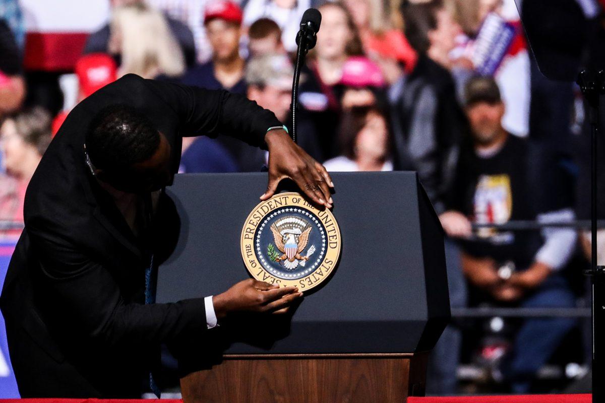 A Secret Service member places the presidential seal on the podium at President Donald Trump's Make America Great Again rally in Wheeling, West Va., on Sept. 29, 2018. (Charlotte Cuthbertson The Epoch Times)
