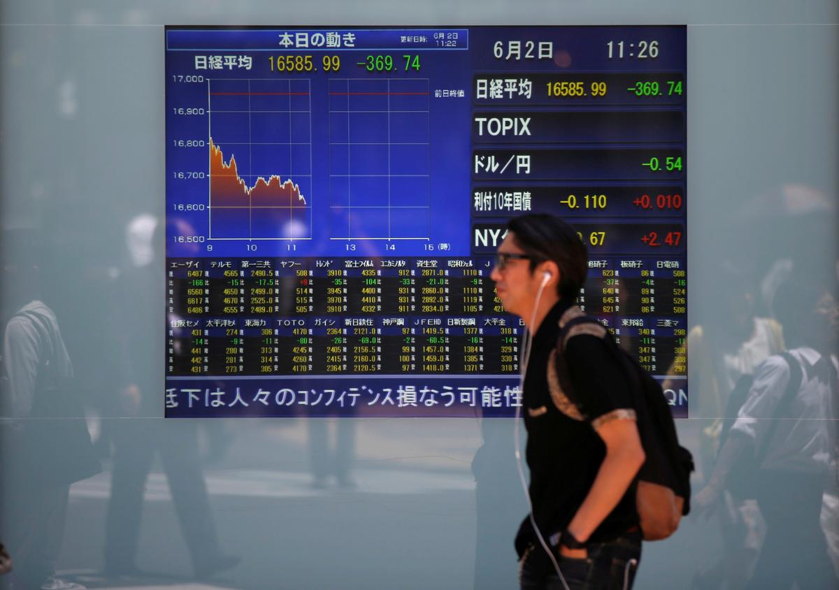 A man walks in front of a screen showing today's movements of Nikkei share average outside a brokerage in Tokyo, Japan, June 2, 2016. (Issei Kato/Reuters)