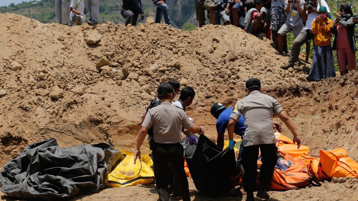 Rescue teams carry the bodies of victims to a mass grave following a major earthquake and tsunami in Palu, Central Sulawesi, Indonesia, on Oct. 1, 2018. (Tatan Syuflana/AP)