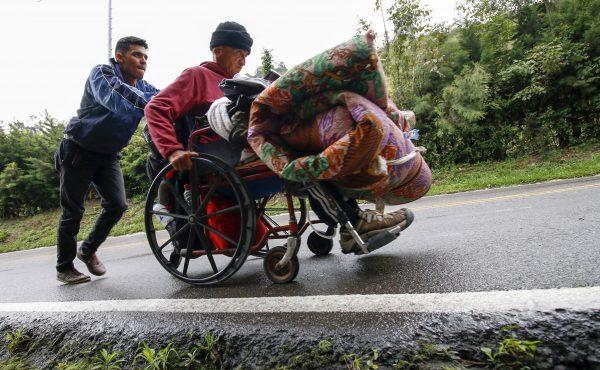 A Venezuelan migrant pushes his father’s wheelchair.