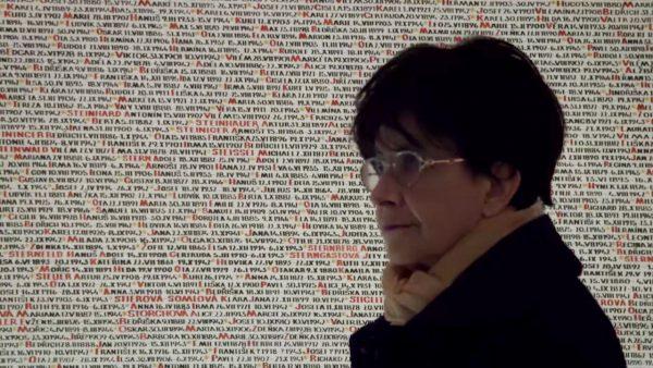 Zuzana Ruzickova stands before a wall of names of those who died in the Holocaust. These are lost "pieces of humanity that can never be made whole," she said. (Zuzana: Music Is Life)