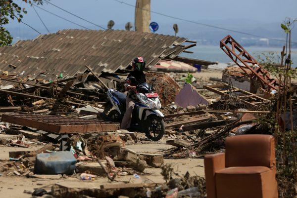 A resident rides her motorcycle among debris after the tsunami in Palu, in Indonesia's Sulawesi Island, Oct. 2, 2018. (Reuters/Beawiharta)