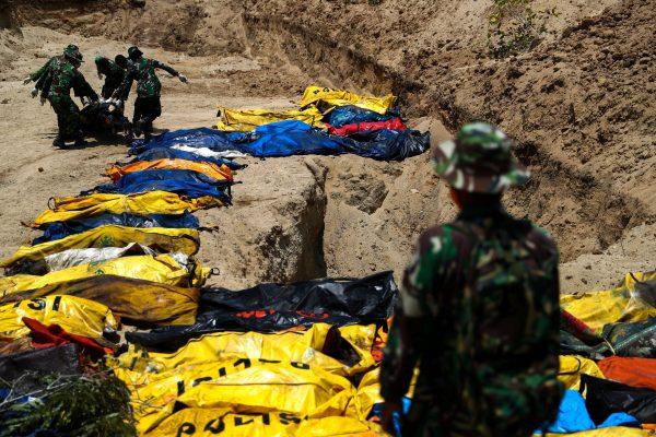 Soldiers move dead bodies of the victims of the earthquake and tsunami during a mass burial at the Poboya Cemetery in Palu, Central Sulawesi, Indonesia, Oct. 2, 2018. (Reuters/Athit Perawongmetha)