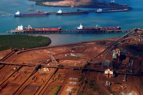 Ships waiting to be loaded are seen near piles of iron ore and bucket-wheel reclaimers at the Fortescue loading dock located at Port Hedland in the Pilbara region of Western Australia on Dec. 3, 2013. (David Gray/Reuters)