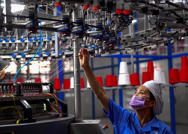 An employee monitors a circular weaving machine at a textile factory in Shangqiu City, Henan Province, China, on Sept. 8, 2018. (STR/AFP/Getty Images)