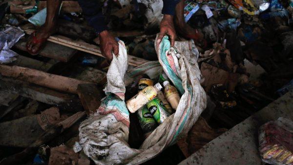 A man put beverages scavenged from an abandoned warehouse into a sack at an earthquake and tsunami-affected area in Palu, Central Sulawesi, Indonesia, on Oct. 3, 2018. (Dita Alangkara/AP)