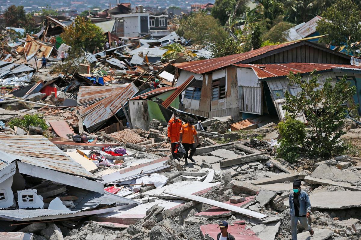 Rescuers carry a body bag containing the remains of an earthquake victim through a neighborhood flattened by Friday's earthquake in Palu, Central Sulawesi, Indonesia Indonesia, on Oct. 2, 2018. (Dita Alangkara/AP)