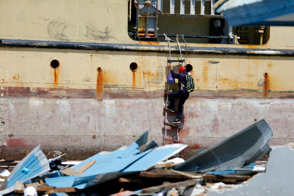 Oct. 4, 2018: A man climbs a rope ladder to board the Sabuk Nusantara 39 ship which was swept ashore by the tsunami in Wani village on the outskirt of Palu, Central Sulawesi, Indonesia Indonesia.(AP Photo/Dita Alangkara)