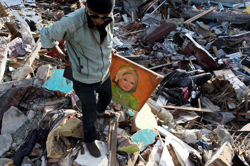 Agus Fardhan carries a portrait of his mother after he found it at her destroyed home, in Palu, Central Sulawesi, Indonesia, Oct. 7, 2018. (ReutersJorge Silva)