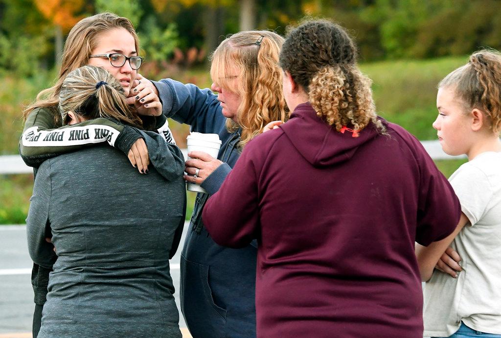 Friends of victims who died in the fatal limousine crash comfort each other after placing flowers at the intersection in Schoharie, N.Y., Sunday, Oct. 7, 2018. (AP Photo/Hans Pennink)