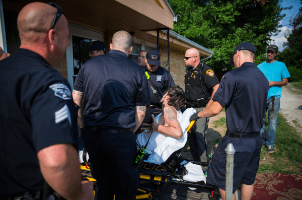 Local police, fire department, and deputy sheriffs help a man who is overdosing in the Drexel neighborhood of Dayton, Ohio, on Aug. 3, 2017. (Benjamin Chasteen/The Epoch Times)