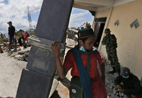 Rescuers take a break at a damaged house during a search for earthquake victims in Balaroa neighborhood in Palu, Central Sulawesi, Indonesia, on Oct. 8, 2018. (Dita Alangkara/AP)