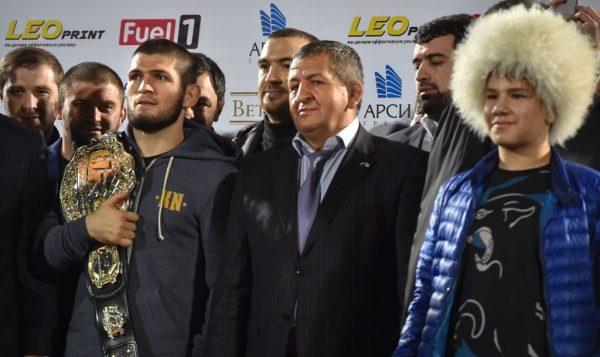 Nurmagomedov (L) holds his UFC belt as he stands next to his father Abdulmanap (C) during a ceremony upon the arrival at the Anzhi Arena stadium in Makhachkala, Dagestan, on Oct. 8, 2018. (Vasily Maximov/AFP/Getty Images)