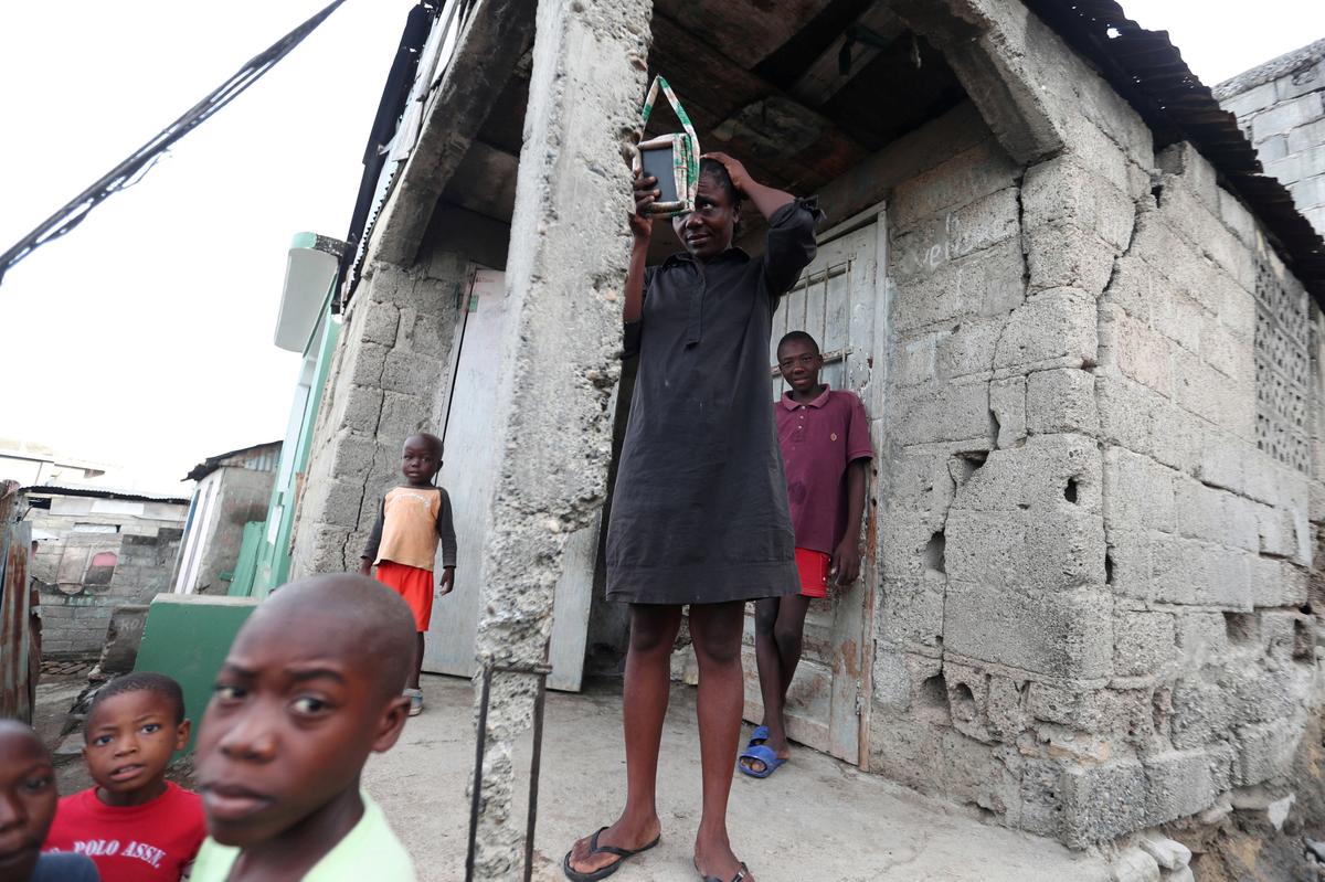 A woman looks at herself in a mirror while standing outside her house after it was damaged in an earthquake, that hit northern Haiti late on Oct. 6, in Port-de-Paix, Haiti, Oct. 8, 2018. (Reuters/Ricardo Rojas)