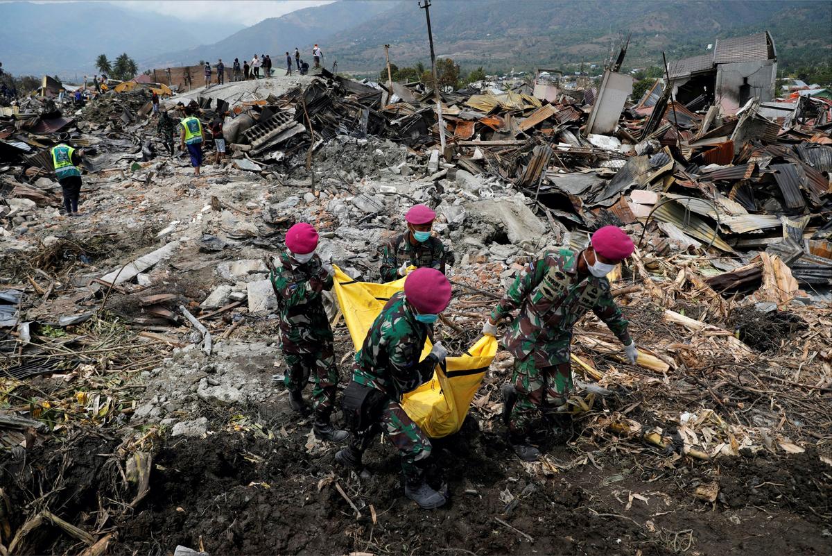 Indonesian soldiers carry a dead body from the ruins of houses after an earthquake hit Balaroa sub-district in Palu, Oct. 4, 2018. (Beawiharta/Reuters)