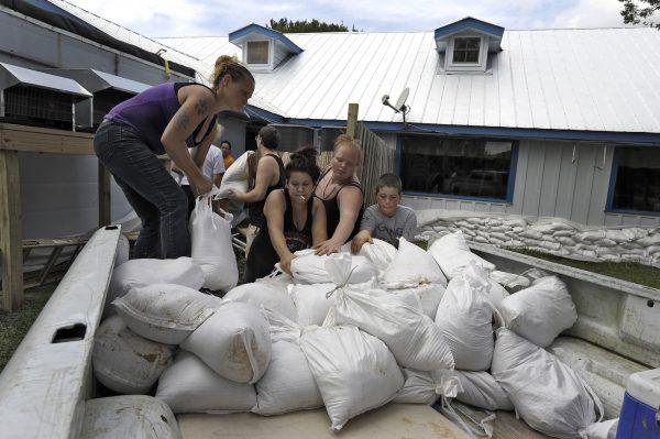 Krystal Day, of Homosassa, Fla., (L), leads a sandbag assembly line at the Old Port Cove restaurant, Oct. 9, 2018, in Ozello, Fla. Employees were hoping to protect the restaurant from floodwaters as Hurricane Michael continues to churn in the Gulf of Mexico heading for the Florida panhandle. (Chris O'Meara/AP Photo)