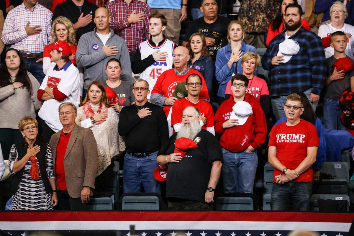Attendees during the national anthem at a Make America Great Again rally in Council Bluffs, Iowa, on Oct. 9, 2018. (Charlotte Cuthbertson/The Epoch Times)