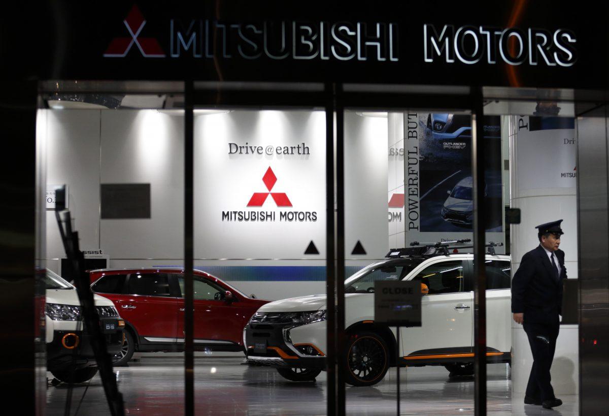 A security worker walks past a Mitsubishi Motors Outlander PHEV sport-utility vehicle displayed at the company's headquarters in Tokyo on April 20, 2016. (Tomohiro Ohsumi/Getty Images)