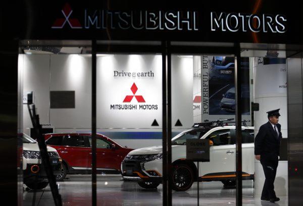 A security worker walks past a Mitsubishi Motors Outlander PHEV sport-utility vehicle displayed at the company's headquarters in Tokyo, Japan, on April 20, 2016. (Tomohiro Ohsumi/Getty Images)