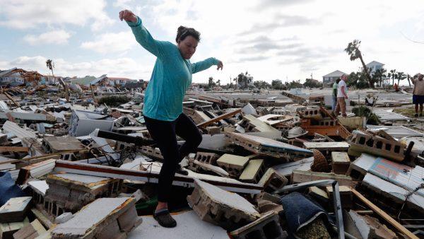 Mishelle McPherson, climbs over the rubble of the home of her friend as she searches for her, since she knows she stayed behind in the home during Hurricane Michael, in Mexico Beach, Fla., on Oct. 11, 2018. (Gerald Herbert/AP)