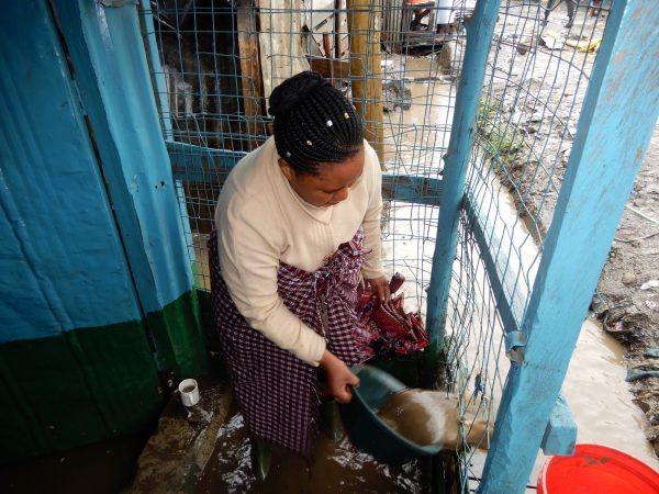 Peninah Mueni removes flood water from her shop in Mukuru Nairobi, Kenya, on March 15, 2018. (Reuben Kyama/Special to The Epoch Times)