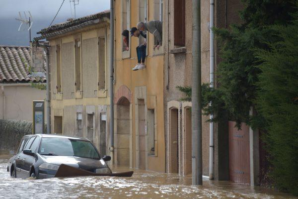 Residents look from their window above cars standing in a flooded street following heavy rains that saw rivers bursting banks in Trebes, near Carcassone, southern France, on Oct. 15, 2018. (Pascal Pavani/AFP/Getty Images)
