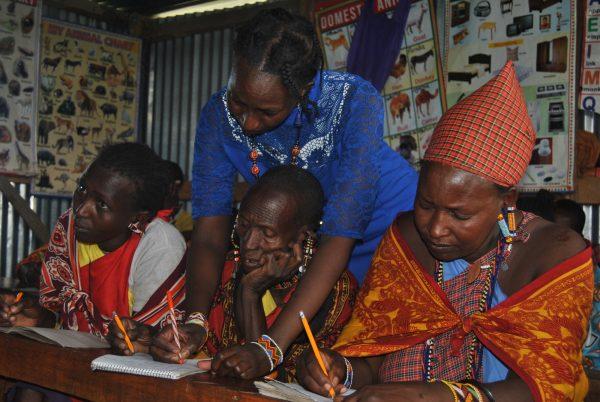 A teacher helps Naatana Karbolo with writing in an adult education class in Narok County, Kenya, on May 4, 2018. (Dominic Kirui/Special to The Epoch Times)