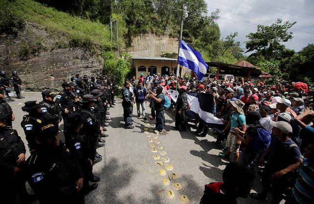 Guatemala's police officers stand as Honduran migrants, part of a caravan trying to reach the United States, arrive at the border between Honduras and Guatemala, in Agua Caliente, Guatemala, on Oct. 15, 2018. (Jorge Cabrera/Reuters)