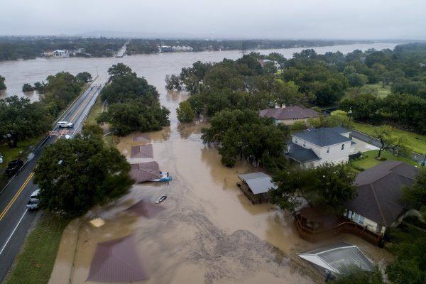 The Llano River overflows its banks into neighboring property as the swollen river flows between the washed out Ranch Road 2900 bridge background in Kingsland, Texas, on Oct. 16, 2018. (Jay Janner/Austin American-Statesman/AP)