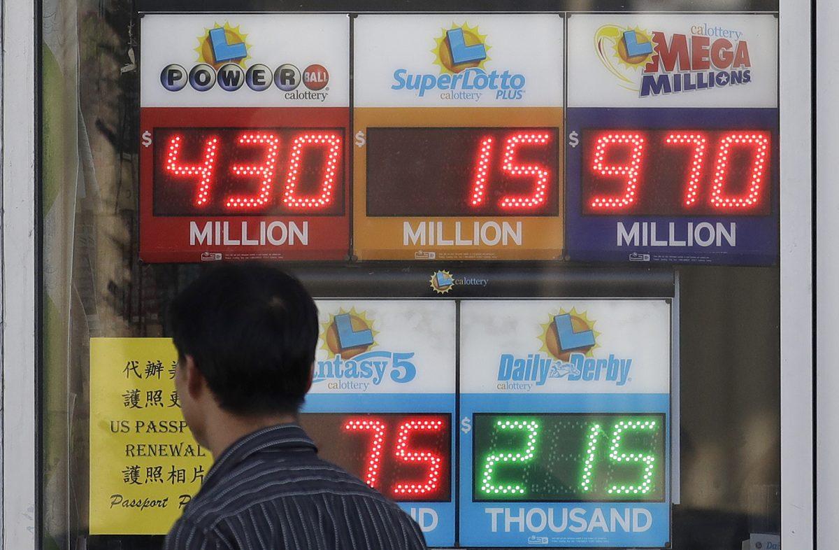 A man walks past Mega Millions and other lottery displays outside of The Lucky Spot in San Francisco, on Oct. 18, 2018. (Jeff Chiu/AP)