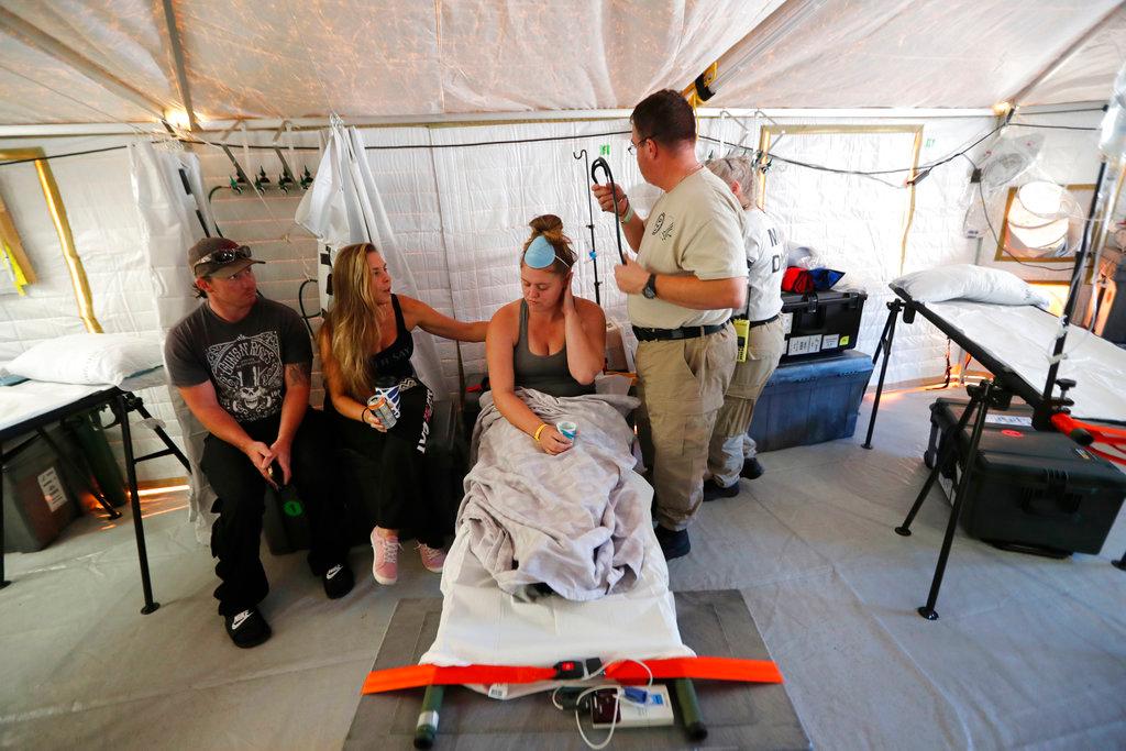 Aleeah Racette receives medical treatment inside the Florida 5 Disaster Medical Assistance Team tent, outside the Bay Medical Sacred Heart hospital, in the aftermath of Hurricane Michael in Mexico Beach, Fla. on Oct. 18, 2018. At left is her mother, Amy Cross, and Amy's fiance, Corey Shuman. (AP Photo/Gerald Herbert)